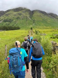 A line of Atmos colleagues walking with their backs to the camera with the first of the three peaks (Ben Nevis) in view in the background