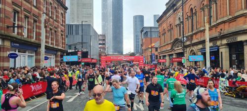 An image of runners finishing the AJ Bell Great Manchester Run in Deansgate with  Beetham Tower viewable in the distance